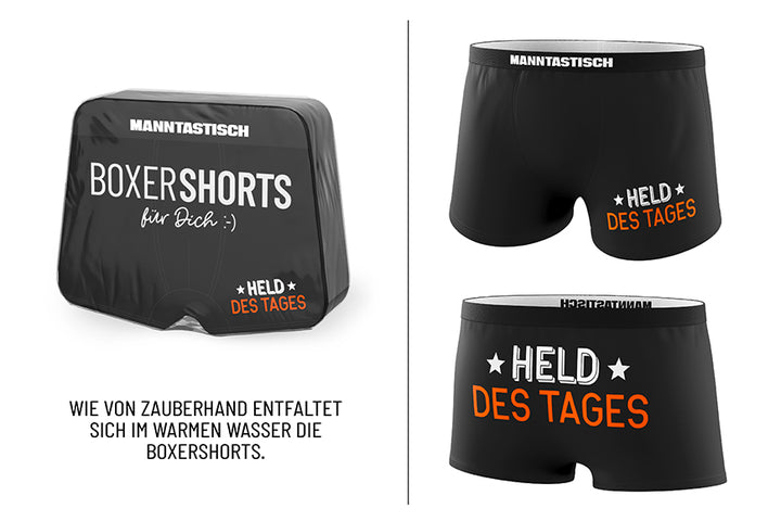 Magische Boxershorts „Held des Tages“ – schwarze Fun-Shorts mit weiß-orangefarbenem Spruch & MANNTASTISCH-Bund von Geschenk für Dich, Männergeschenk