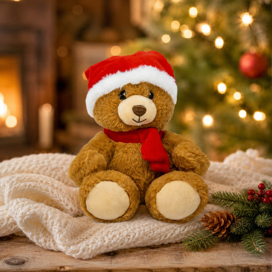 Weihnachtsbär Kuscheltier mit Mütze und Schal in festlicher Weihnachtsszene mit Lichtern