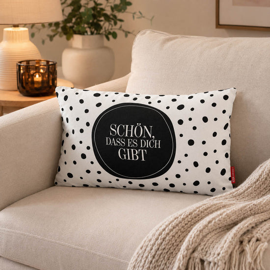 Kissen mit Spruch Schön, dass es Dich gibt im schwarz-weißen Punkte-Design, weiße Rückseite, auf Bettwäsche
