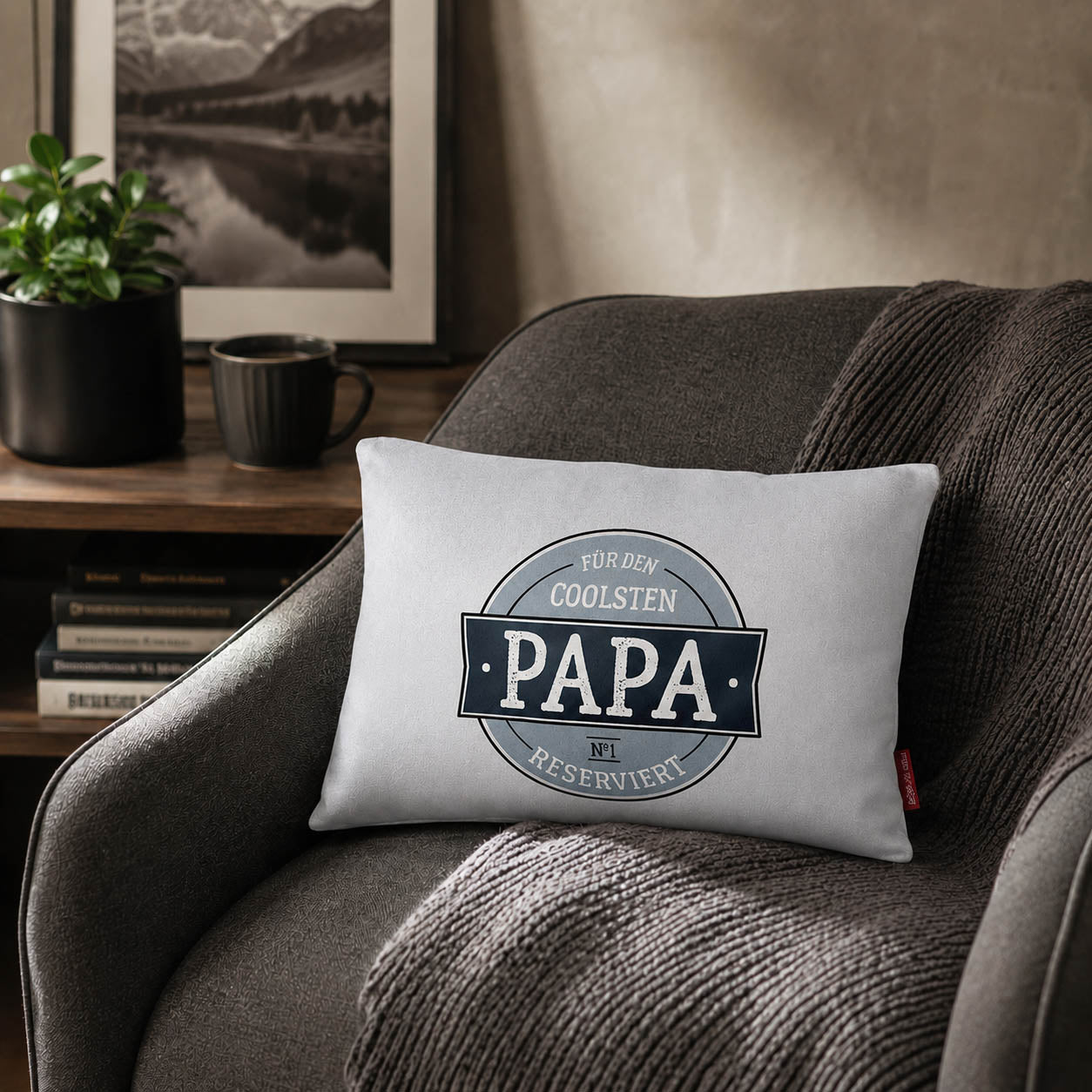 Graues Kissen „Für den coolsten Papa reserviert“ auf dem Sofa – Geschenk zum Vatertag