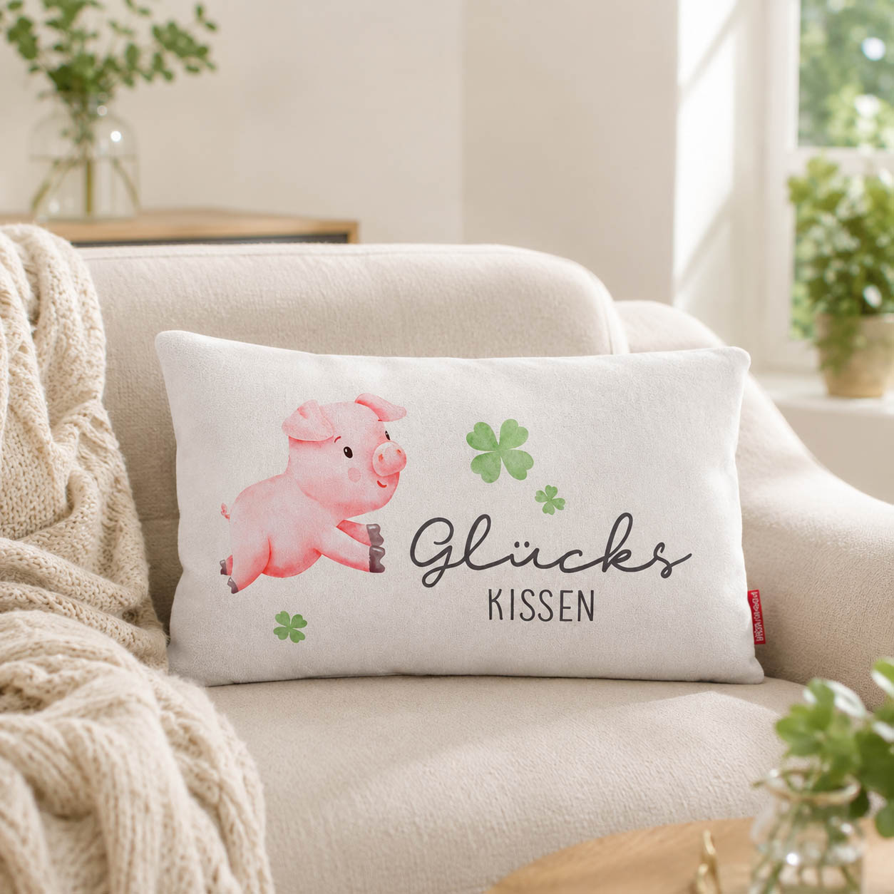 Glückskissen mit Glücksschwein und Kleeblatt-Motiv, grüne Rückseite, auf hellem Holz