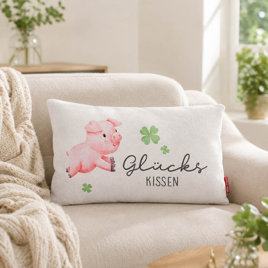 Glückskissen mit Glücksschwein und Kleeblatt-Motiv, grüne Rückseite, auf hellem Holz