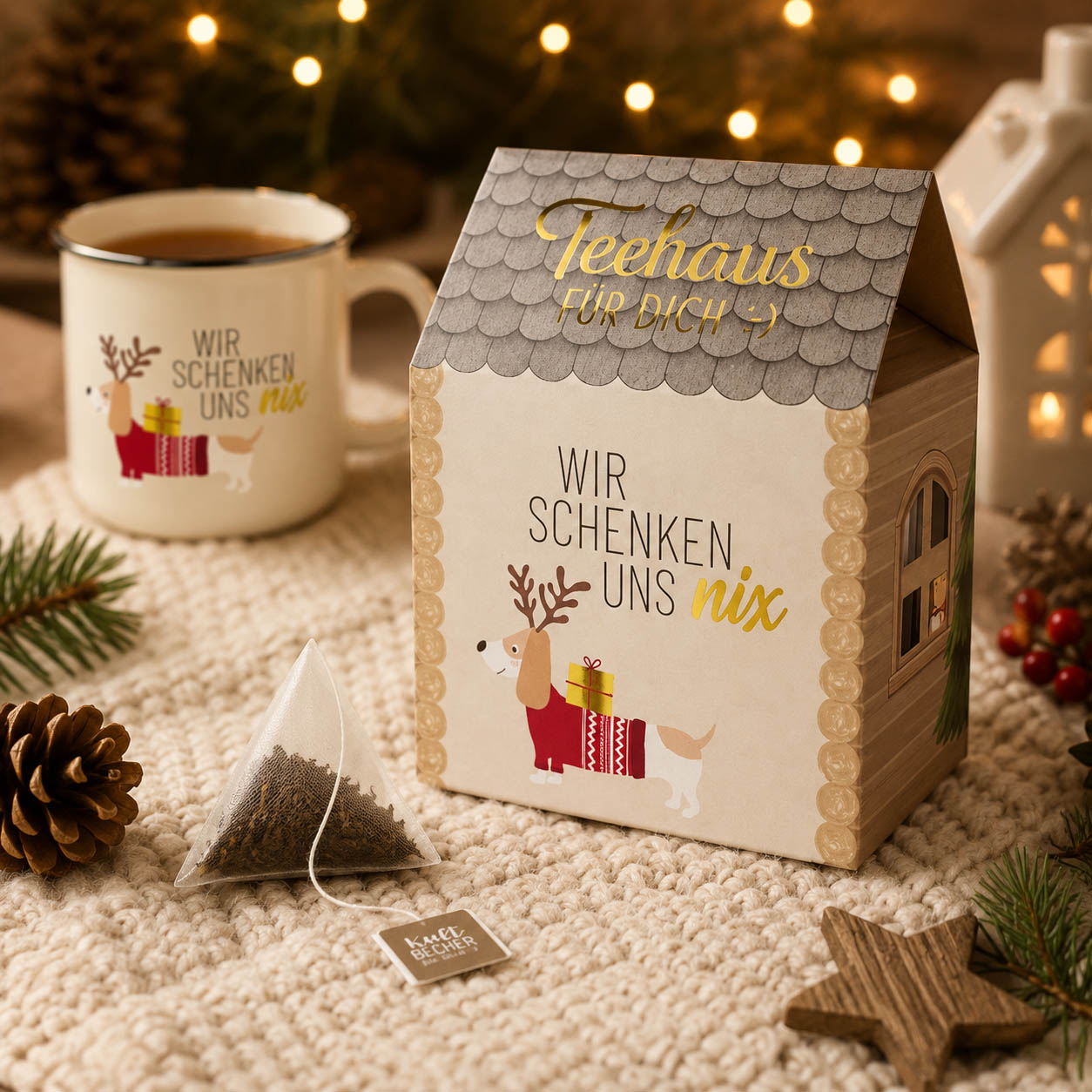 Teehaus Wir schenken uns nix mit dampfender Tasse Tee und Teepyramide auf kuscheliger Weihnachtsdecke