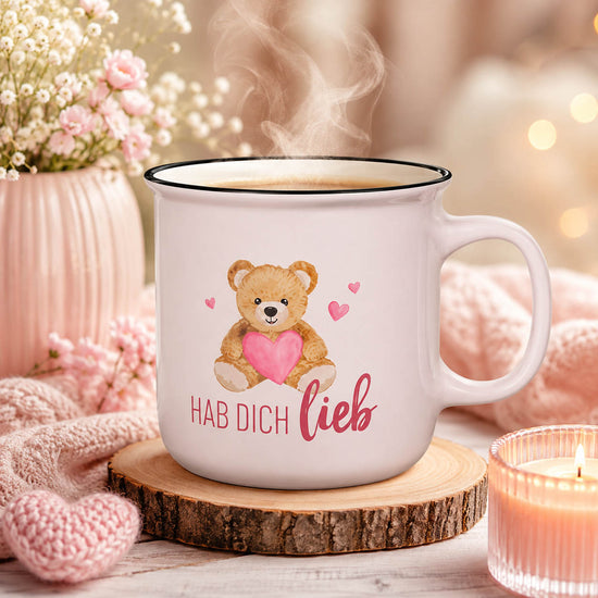 Kultbecher „Hab Dich lieb“ in Zartrosa mit Teddy und pinkem Herz, stimmungsvoll auf einer Holzscheibe mit Strickdecke, Häkelherz und Kerze – Geschenk für Dich