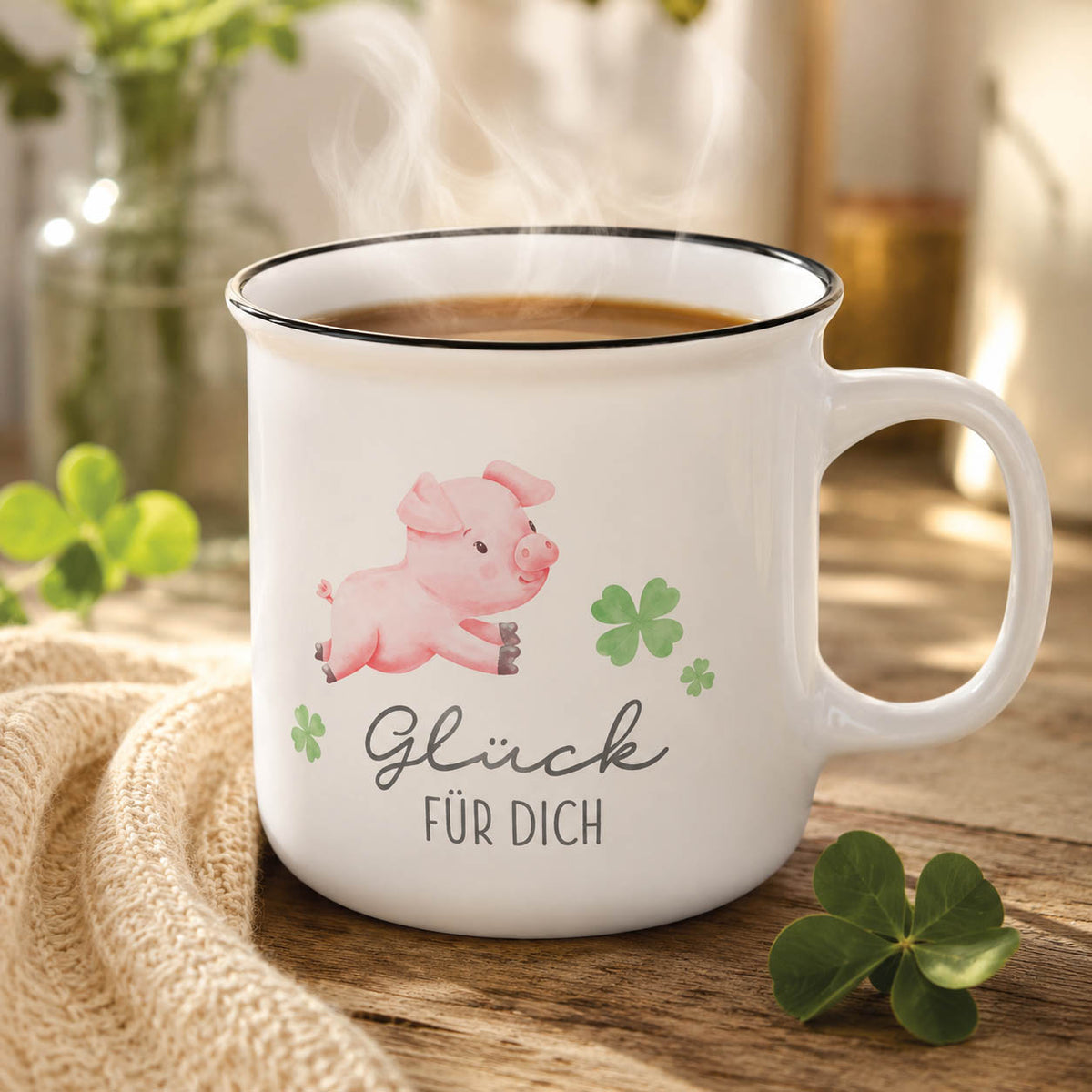 Kultbecher „Glück für Dich“ in Weiß mit Glücksschweinchen, stimmungsvoll auf Holztisch mit vierblättrigen Kleeblättern und Strickdecke – Geschenk für Dich